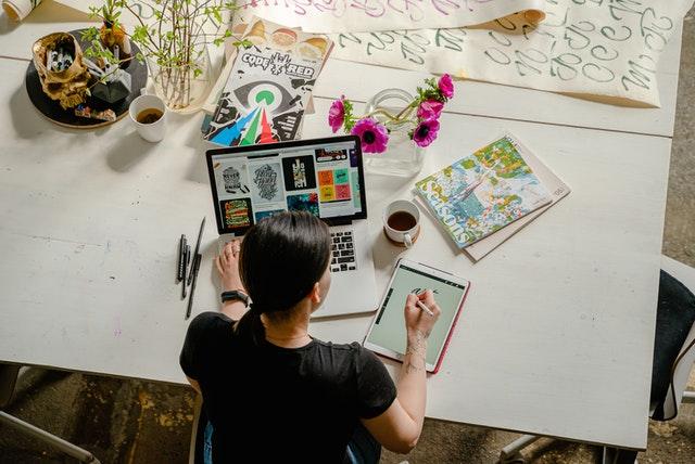 Female sat at desk working on computer writing on notepad